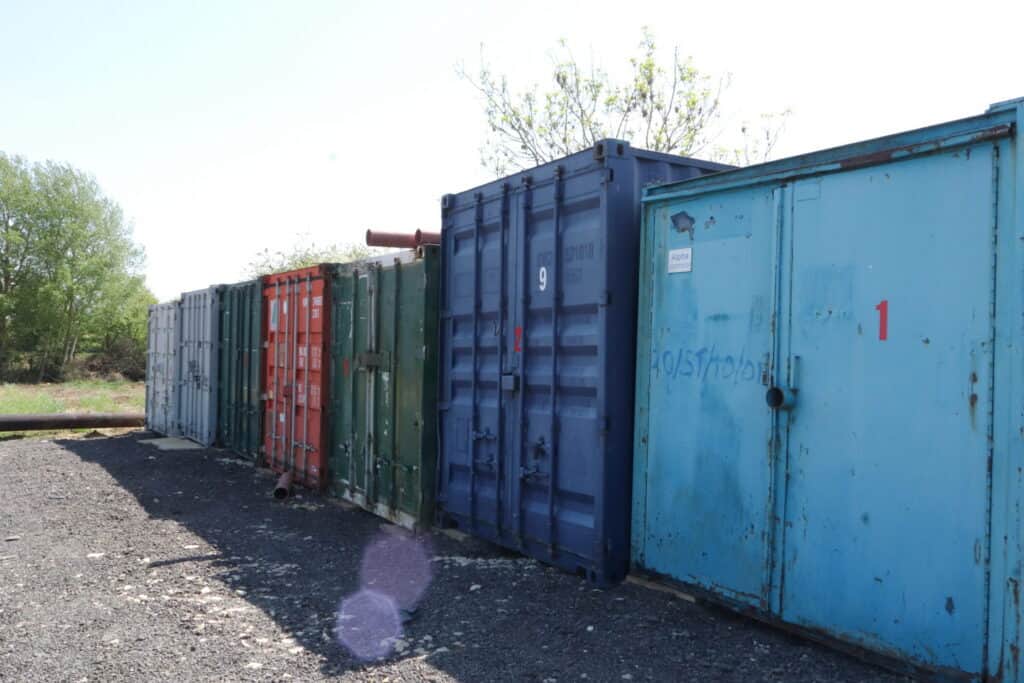 Row of colorful shipping containers in an outdoor storage area.